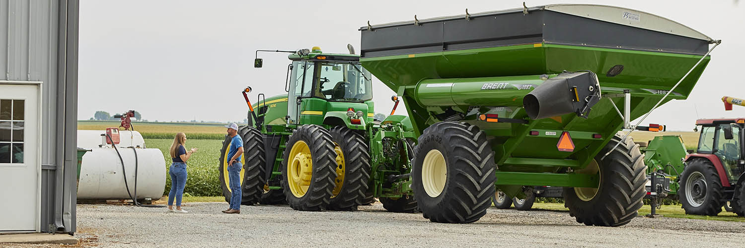 man and woman standing near green tractors