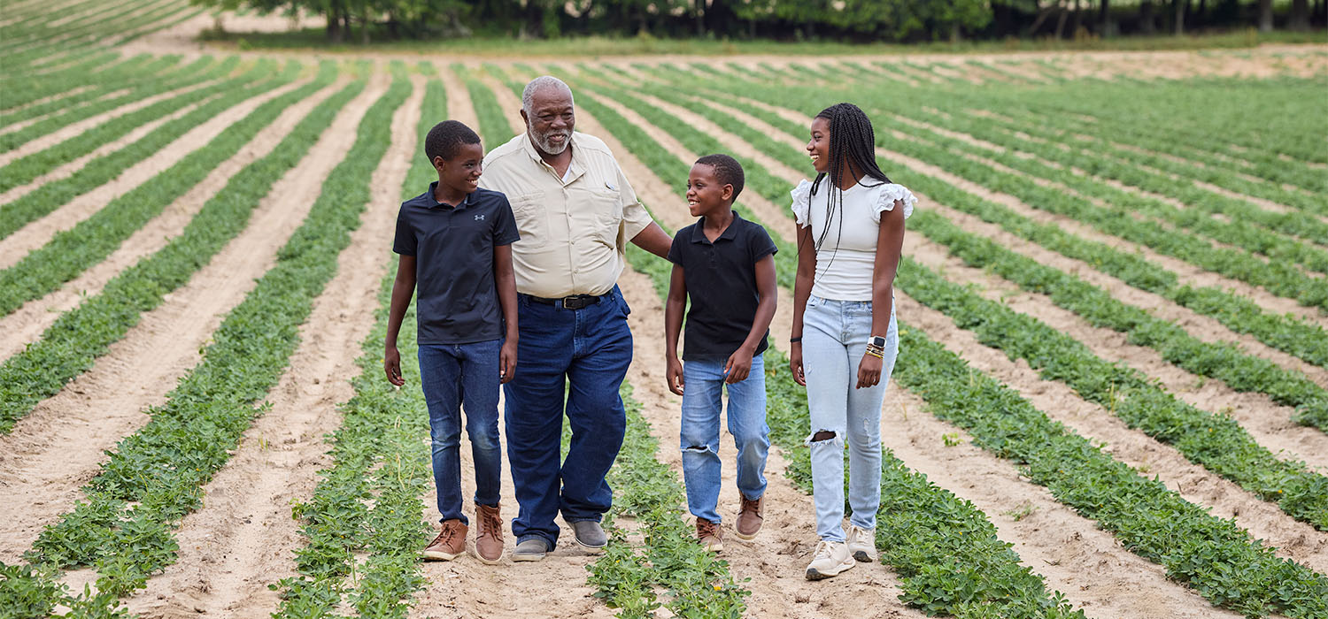 Producer Howard Hodge and his three grandkids walking through farmland